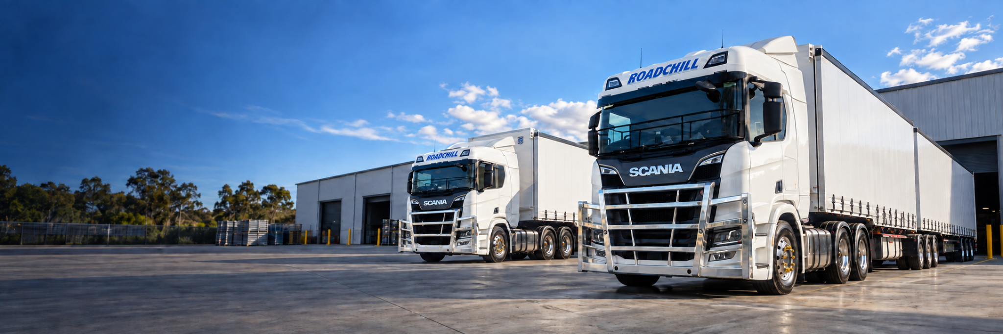Two white Roadchill Scania freight trucks parked at the depot